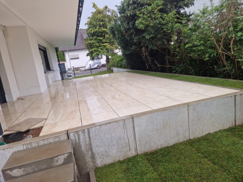 Fertige Terrasse mit großformatigen Platten und angrenzendem Rasen
