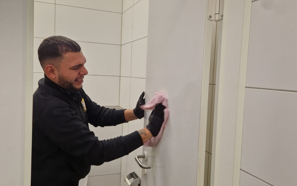 Mitarbeiter der Yulian Bau Gebäudereinigung bei der Desinfektion einer Sanitärtür